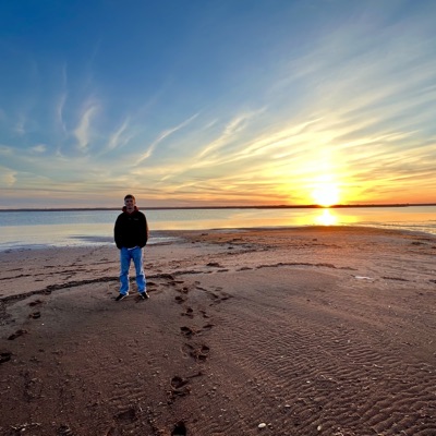 Matthew Finnegan standing on a beach at sunset